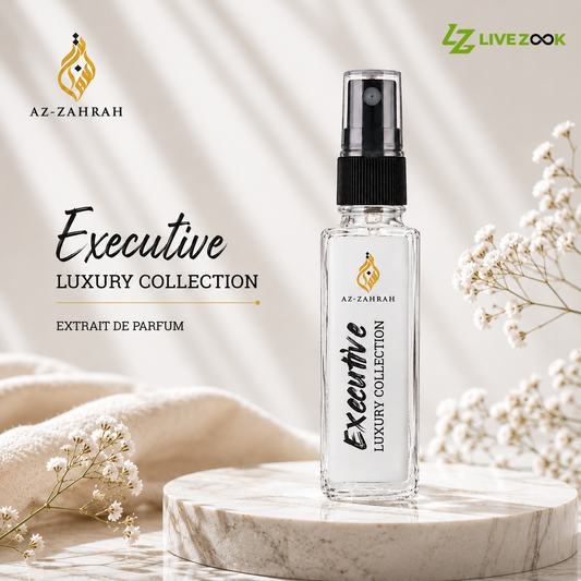 A clear glass perfume spray bottle labeled 'Executive Luxury Collection' by Az-Zahrah, standing on a round marble pedestal with soft cream fabric and white flowers around it. The image includes promotional text and the LIVEZOOK logo.