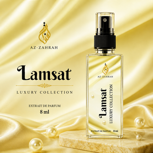 A clear rectangular perfume spray bottle labeled 'Lamsat Luxury Collection' with a black pump, standing on a light stone pedestal against a draped gold satin background with pearl props. The brand name 'AZ-ZAHRAH' is visible on the bottle and as a logo on the left.